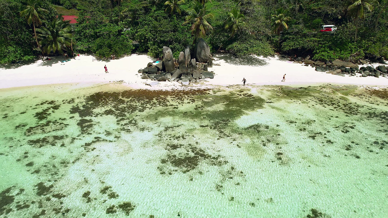Mahe Seychelles reveal shot of people on the beach, rock boulders